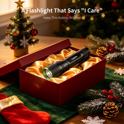 A black Lepro flashlight with a green accent ring rests inside an open red gift box lined with gold satin, surrounded by Christmas decorations including a tree, stockings, pinecones, and evergreen branches. Text at the top reads, 'A Flashlight That Says "I Care" Make This Holiday Brighter'.